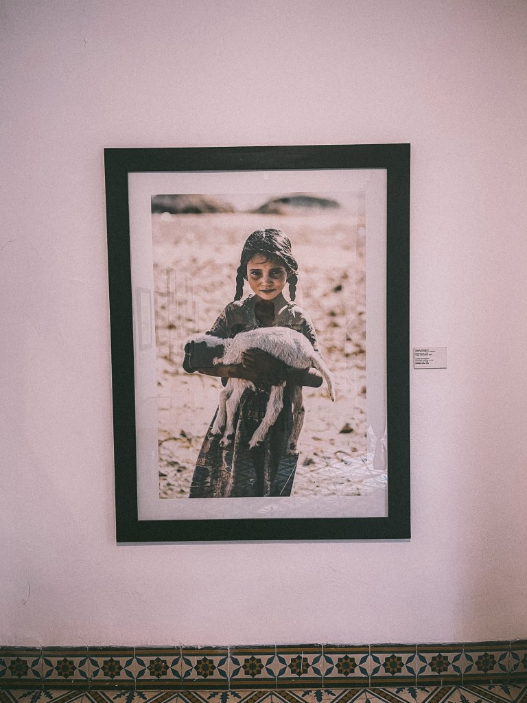 Framed photograph of a young girl holding a goat, with a soft focus background.