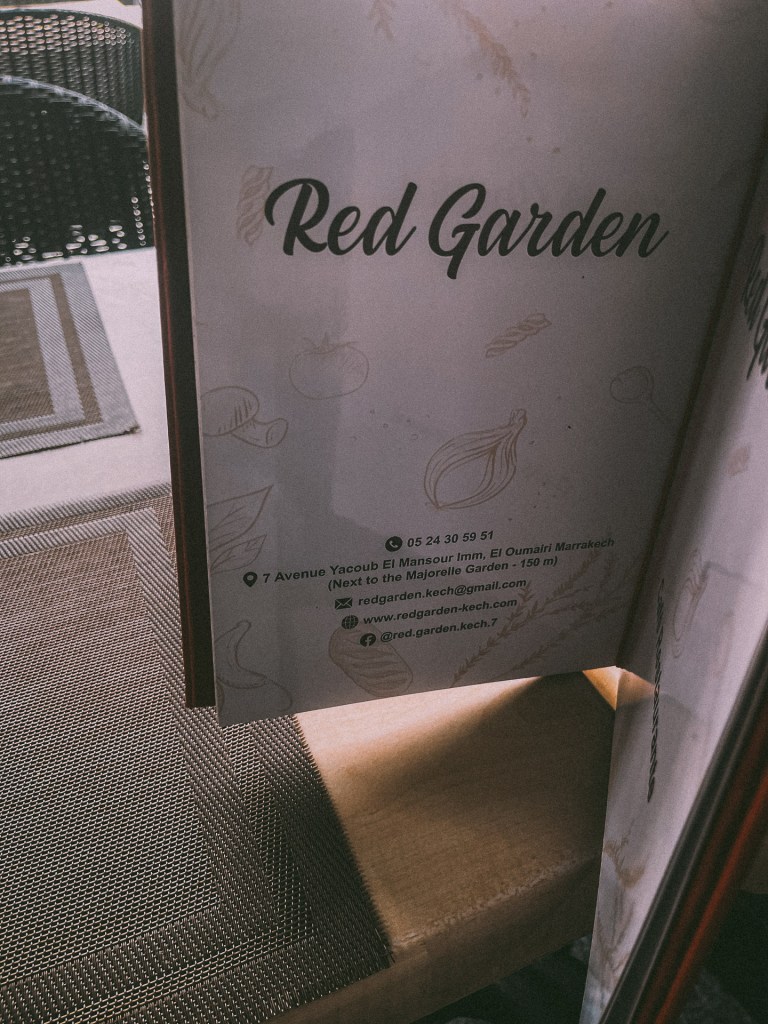 Close-up of a restaurant menu titled 'Red Garden' with contact information and location details in Marrakech.