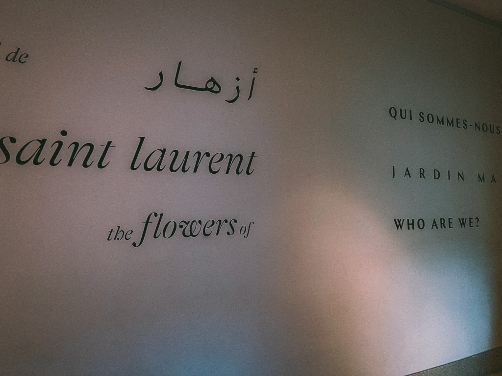 Textual wall art featuring phrases in Arabic, French, and English about flowers and the Jardin Majorelle, at the Yves Saint Laurent Museum.