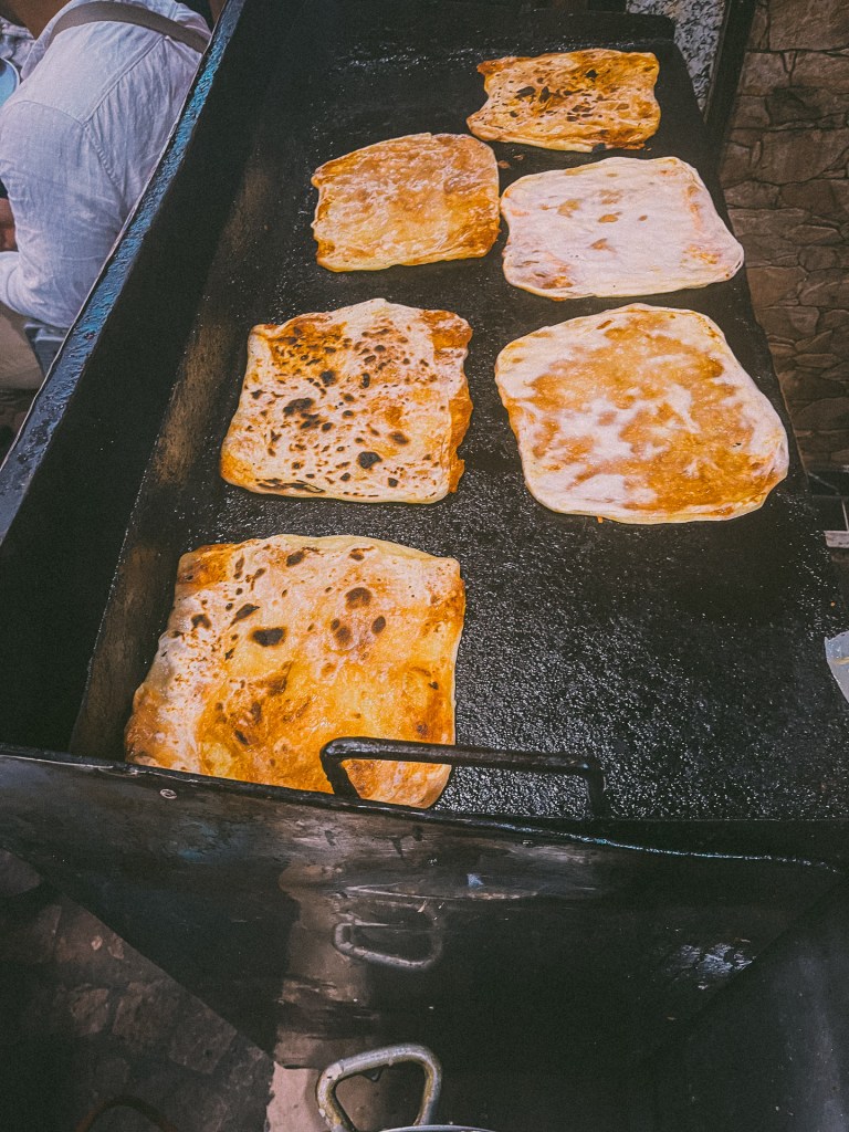 A close-up view of freshly cooked Moroccan Msemmen, a traditional pancake-like bread, being prepared on a hot griddle.